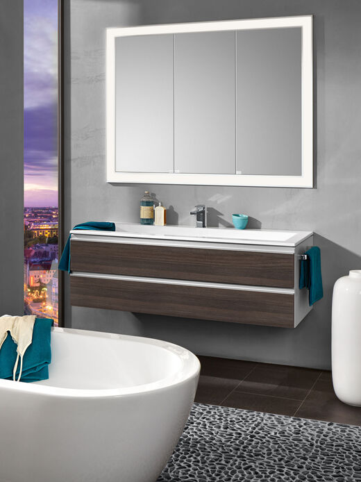 Der Spiegelschrank Future 2.0 eingefasst von LED-Lichtbändern und einem Waschtisch von heibad.