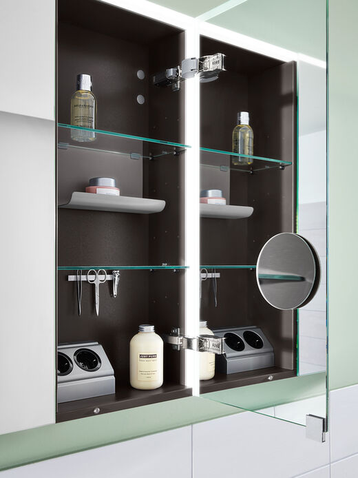 Spiegelschrank offen mit Magnetleiste, Kosmetikspiegel und Steckdosen.