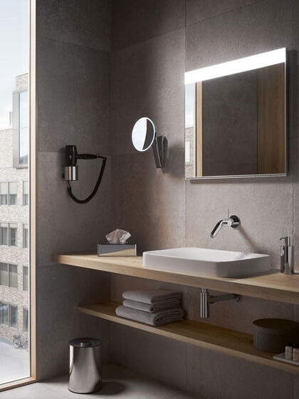 Waschplatz in einem Hotelzimmer-Ambiente: Neben einem großen Spiegel ist auch ein runder Vergrößerungsspiegel der Serie iLook move von KEUCO angebracht.