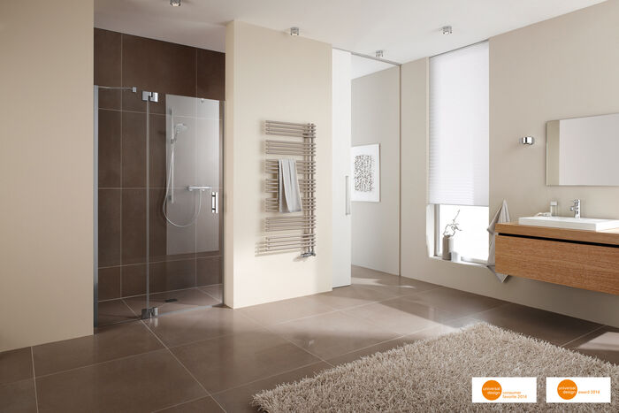 Designheizkörper im asymetrischen Design wandmontiert im Badmilieu mit Dusche und Waschplatz.
