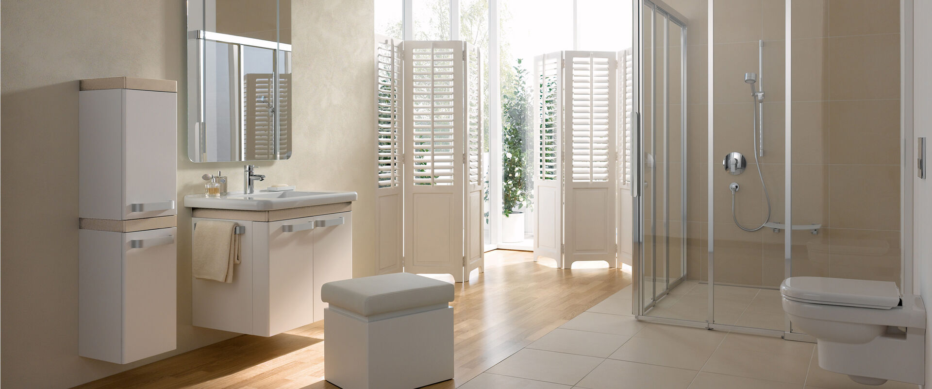 Milieubild eines Komfortbades. Waschbecken mit unterschrank, der geöffnet unterfahrbar ist sowie ein spiegel und Hochschrank. Wandmontierte Toilette auf der gegenüberliegenden Seite und eine begehbare Dusche.