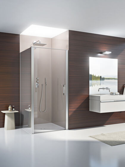 Badezimmer, in dem in der Dusche eine Duscholux_PanElle_enlight Wandverkleidung installiert ist. Rechts befindet sich ein Waschbecken mit Spiegel.