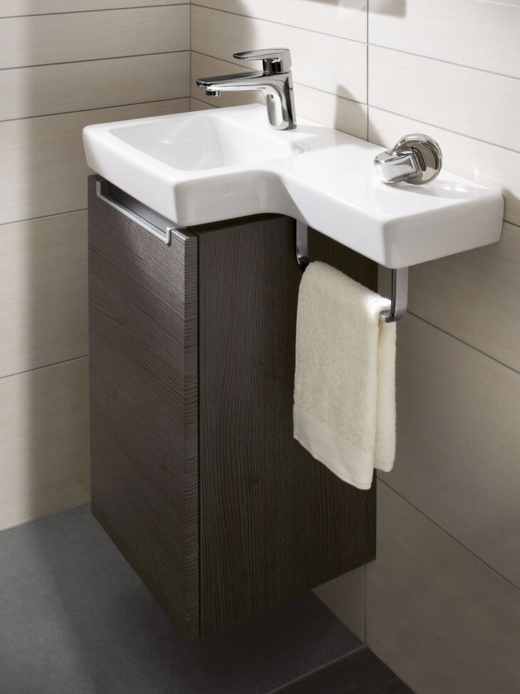 Kleiner Waschplatz mit Aufsatzwaschbecken auf braunem Badmögel. Keramik verlängert mit seitlicher Ablage und Handtuchhalter in Chrom.