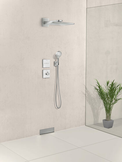 In beige gehaltene, bodenebene Dusche, in der eine hansgrohe raindance select Kopfbrause installiert ist. Hier einer Glaswand steht eine Pflanze.