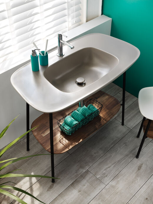 VitrA Plural Beigefarbenes Waschbecken der Serie VitrA Plural mit stabilen Standfüßen und integrierter Ablage unter dem Becken.