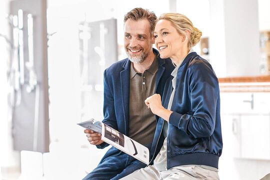 Kundenpaar in der Badausstellung, das sich mit einem Katalog ausgestattet über die Inspiration freut.