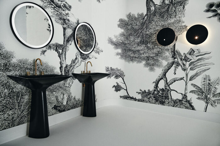 Zwei schwarze Waschtische Tipo-Z von Ideal Standard nebeneinander vor einer weißen Wand mit schwarzen Blumenornamenten. 