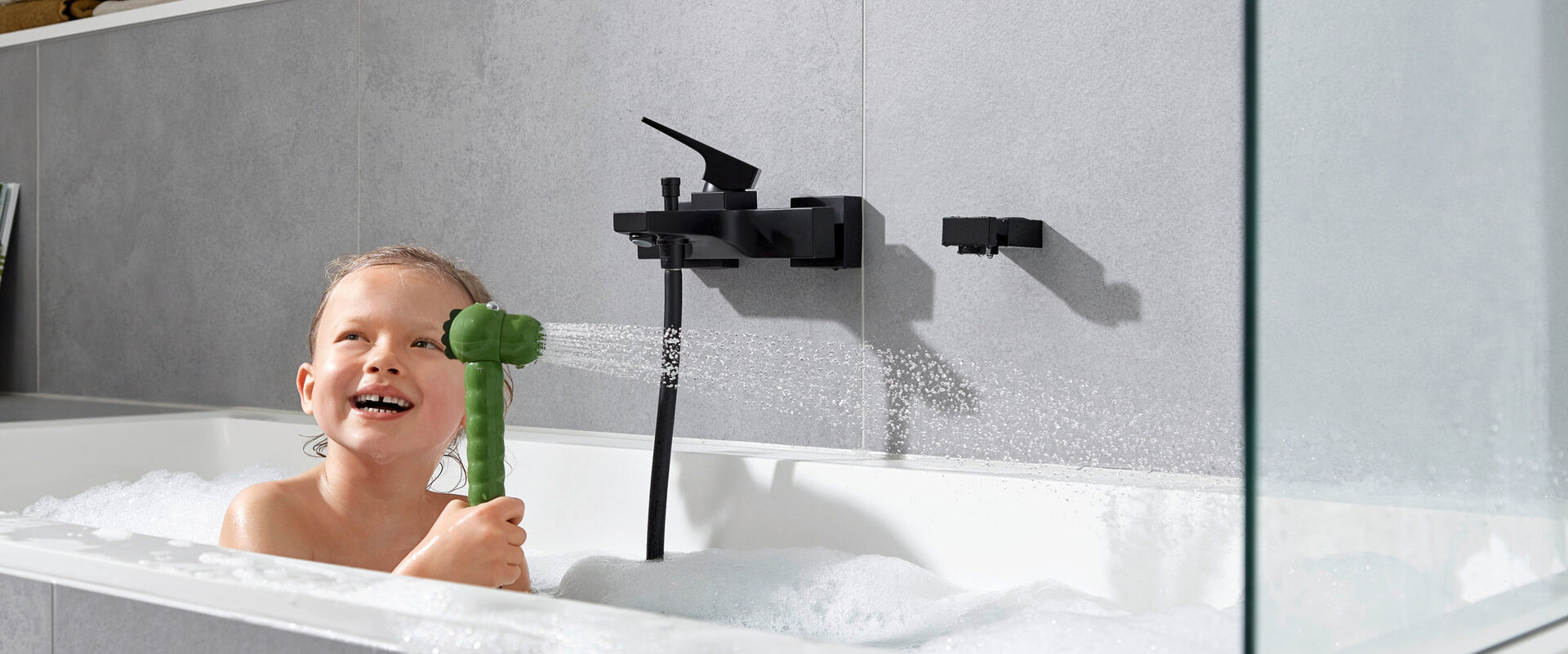 Kind hat Spaß in der Badewanne mit der Kinderbrause Jocolino von hansgrohe