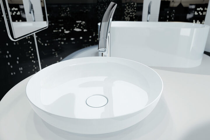 Weißes, rundes Waschbecken Miena von Kaldewei, dass sich auf einem Waschtisch befindet. Im Hintergrund ist eine Badewanne zu erkennen.
