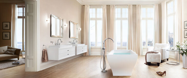 Frohes Helles Badezimmer mit Freistehender Badewanne, Waschbecken, und Spiegeln. An den verschiedene Elementen sind Grohe Grandera Badarmaturen installiert.