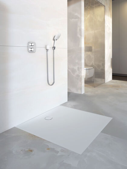 Helles Badezimmer, in dem eine bodenebene Dusche installiert ist. Die Duschfläche Setaplano von Geberit hat eine graue Farbe.