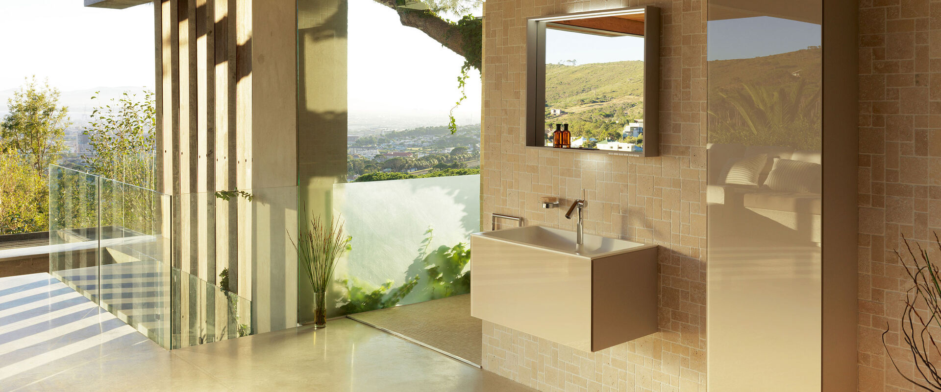 Badezimmer mit südlichem Charme in warmen Farben. Waschbecken und Badmöbel in beige sowie Badspiegel.