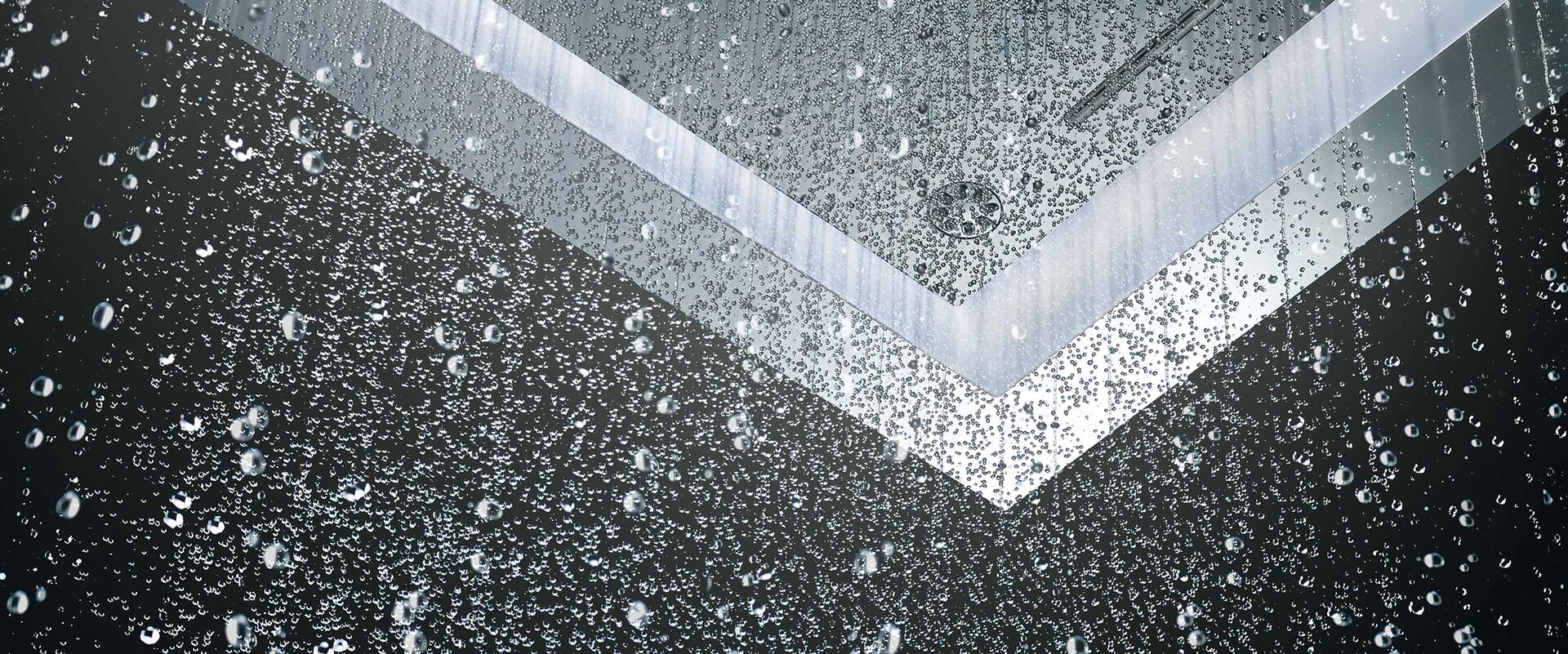 Beleuchtete Regendusche deckenmontiert mit Wassertropfen.