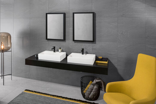 Badgestaltung von Villeroy & Boch mit Kontrasten: Currygelber Sessel trifft auf s/w Waschplatz im Bad, der mit zwei rechteckigen Memento 2.0 Aufsatz-Waschbecken ausgestattet wurde. 