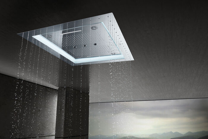 Aus der GROHE Aqua Symphonie Regendusche fließt Wasser heraus. Die Regenduschen ist in einem Raum mit geheimnisvollem Licht installiert.