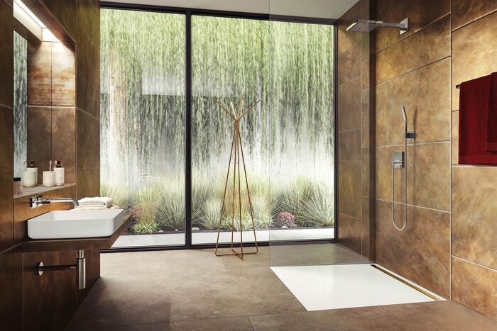 Frei begehbare Dusche Nexsys mit integrierter Rinne von Kaldewei. Badezimmer mit großer Fensterfront, Waschbecken und offener Dusche.