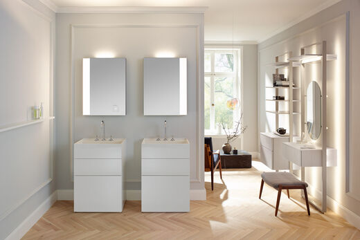 Modernes Doppel im Altbau-Ambiente: Zwei kompakte Waschsäulen aus dem Programm RC40 von burgbad in zartem Weiß Hochglanz mit beleuchteten Spiegeln.