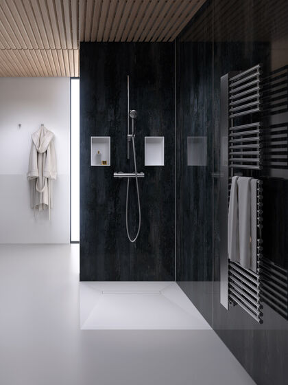 Dusche, in deren Duschwand als Ablageflächen zwei Duschboards Multistar Plan Plus von Schedel eingelassen sind. Rechts hängen Handtücher an einer Heizung, links hängt ein Bademantel im Hintergrund.