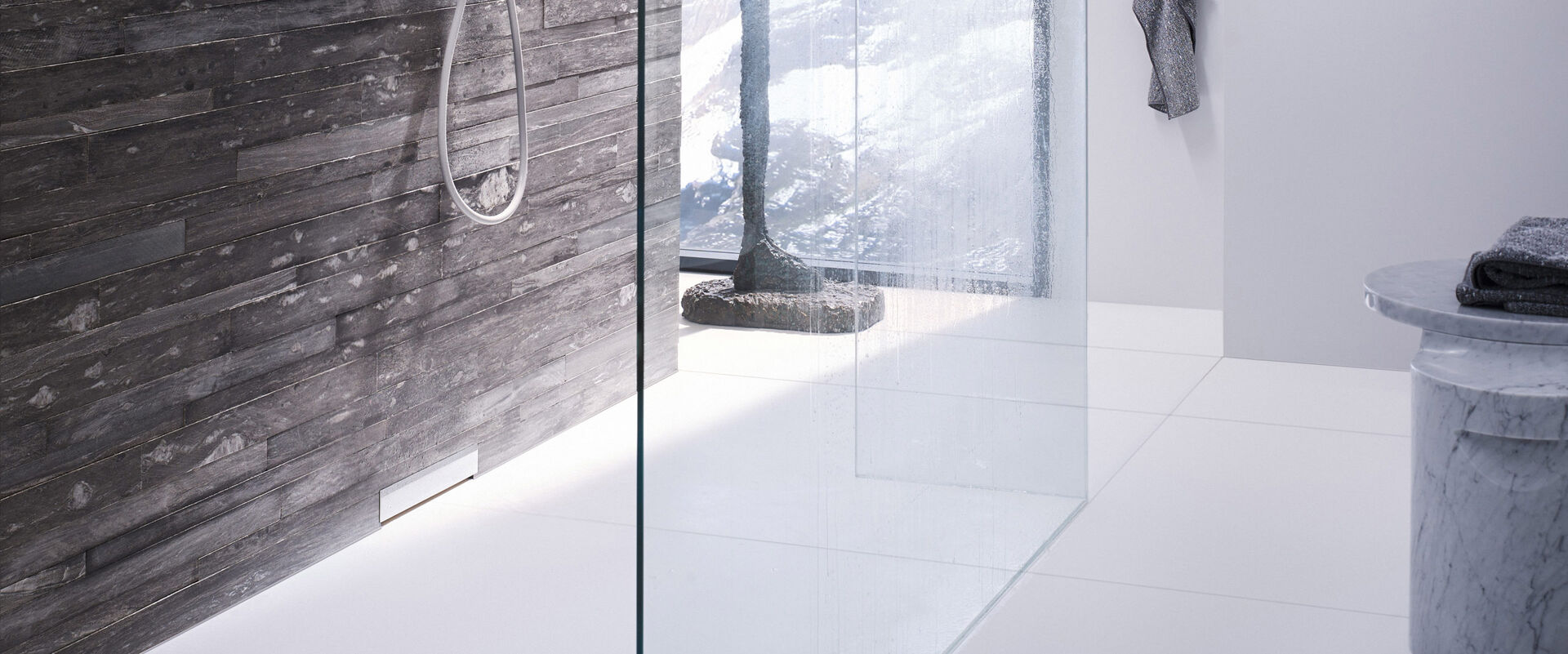Badezimmer mit einer Dusche, in der ein Geberit Wandablauf installiert ist. Die Dusche ist mit einer Glaswand ausgestattet. 