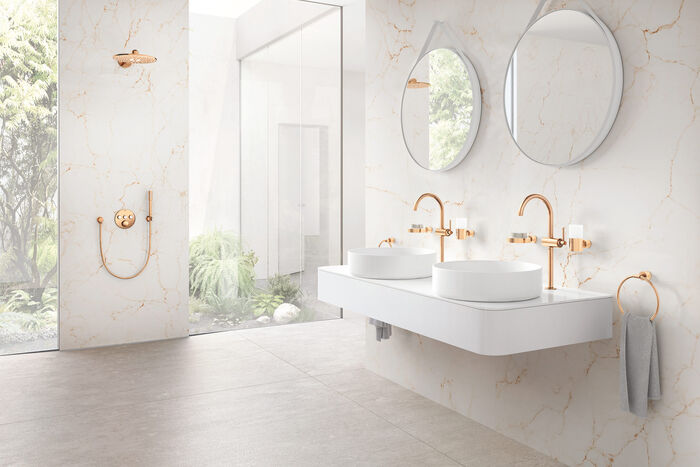 Lichtdurchflutetes Luxusbad mit weißem Marmor, Dusche, Doppelwaschtisch, runden Spiegeln und edlen Armaturen und Accessoires von Grohe in der Oberfläche Warm Sunset.
