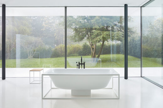 Design Badewanne in weißem Stahlgestell. Hintergrund Blick in den Garten.
