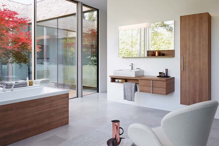 Komplettes Bad mit Holz-Badmöbeln und Badewanne. Waschplatz mit Spiegel, Waschbecken und Schränken.