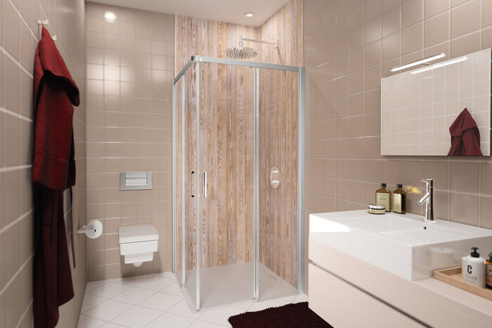 Beige gefliestes Badezimmer, in dessen Dusche eine EasyStyle Wandverkleidung von HUEPPE in Holzoptik angebracht ist. Links befindet sich eine Toilette, rechts ein Waschbecken mit Spiegel.