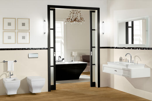 Freistehende Badewanne aussen schwarz. Im Vordergrund Waschplatz mit Spiegel sowie Bidet und Toilette.