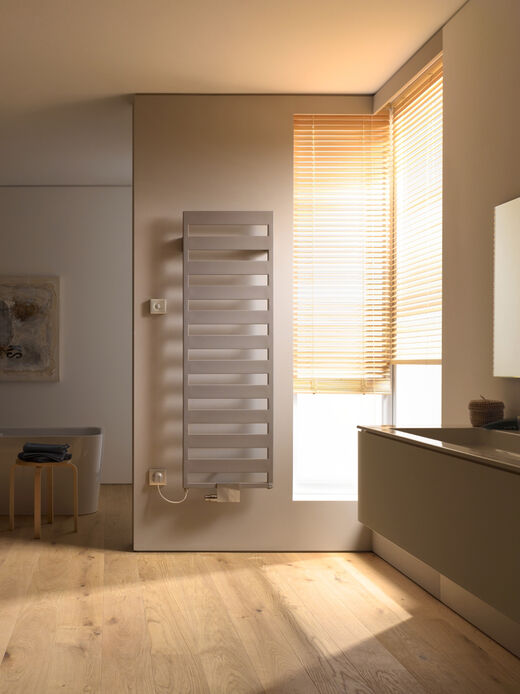 Designheizkörper beige mit elektroanschluss in der Abendsonne im Badezimmer