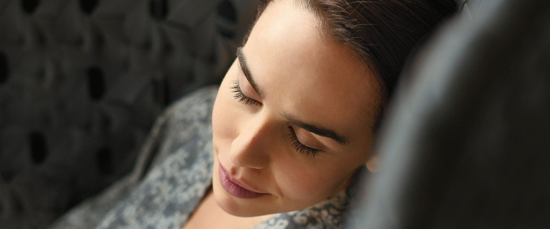 Frau entspannt in einem Kormstuhl mit geschlossenen Augen.