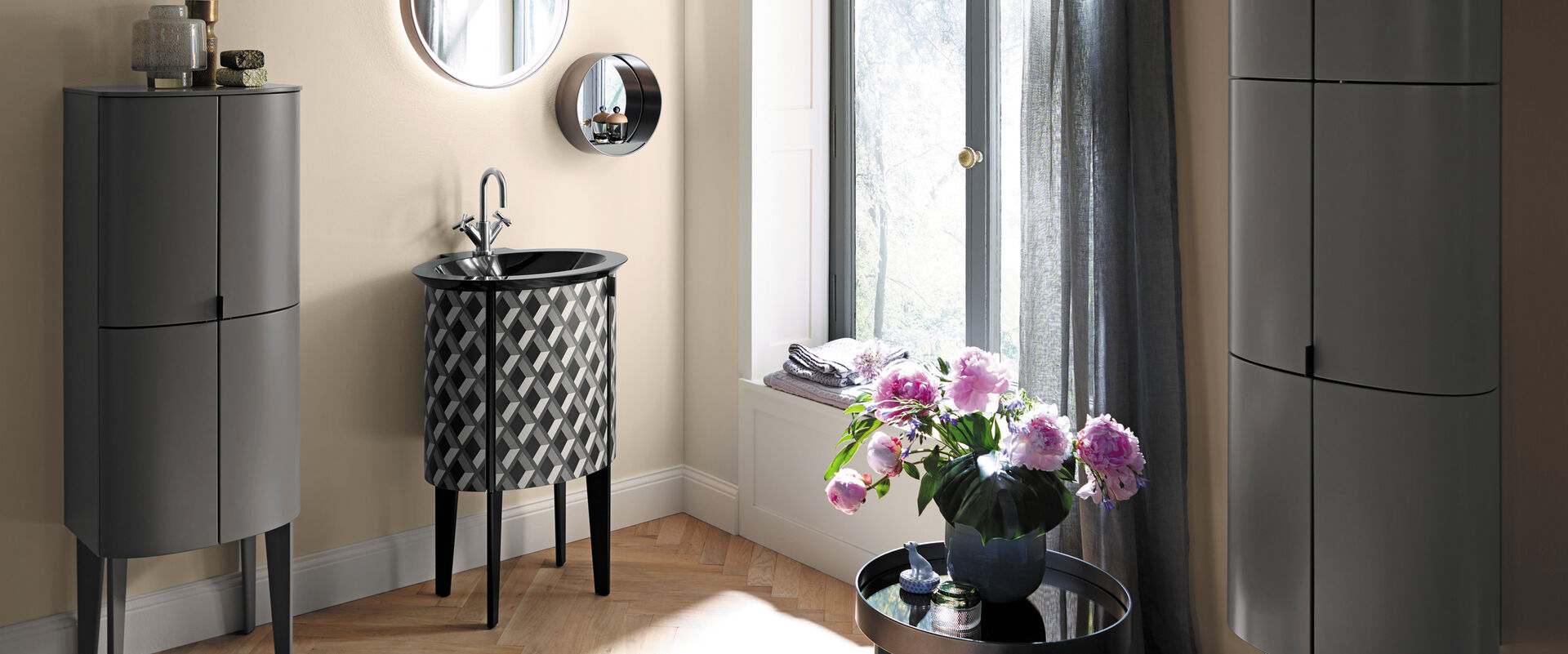 Bad für Gäste mit grauen abgerundeten Badmöbeln. Waschbecken in schwarz weiß. Runde Spiegel