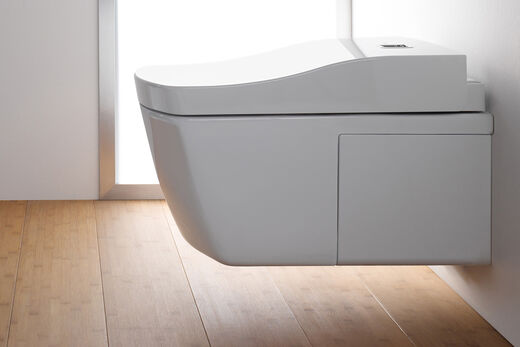 An der Wand hängend montiertes Dusch-WC von TOTO aus der modernen Serie Neorest. Kompaktes Design und klare Formensprache. Seitenansicht mit Holzboden.