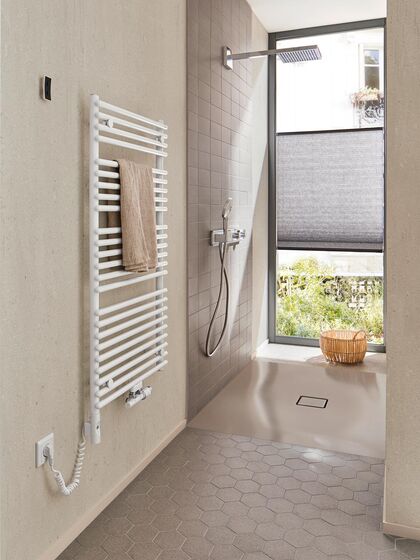 Offener Duschbereich einer Fitnessbadplanung von Kaldewei mit bodenebenen Duschfläche Conoflat in edlem Pasadenagrau, Regenbrause und praktischem Handtuch-Heizkörper.