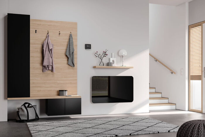 Designorientierter, schwarzer Glasheizkörper Elveo von Kermi im Querformat montiert im Hauseingangsbereich.