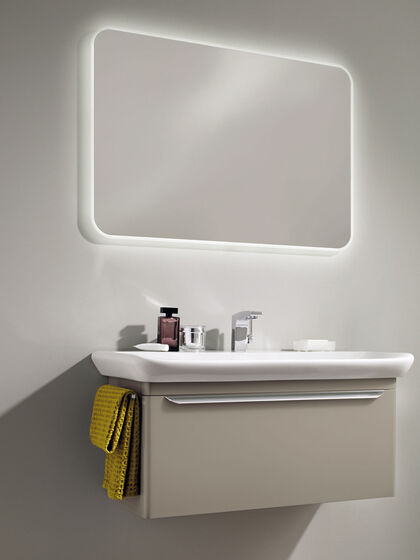 Badspiegel beleuchtet mit Badmöbel in beige und Waschbeckeneinsatz.