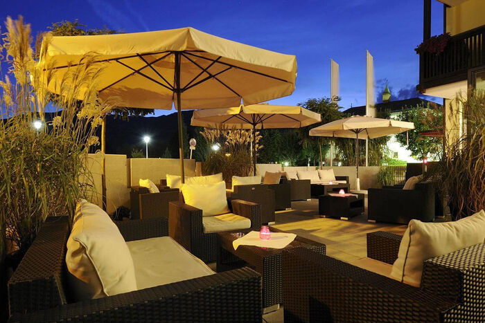 Terasse mit Loungemöbeln und Sonnenschirm in der Abendstimmung im Hotel Ritzenhof am See.