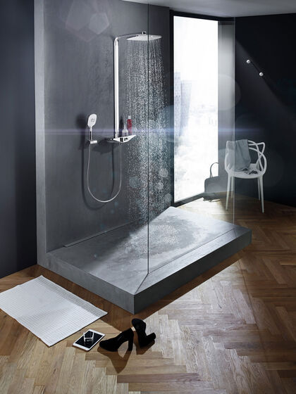 In Betonoptik gehaltene Dusche mit Glaswand als Abtrennung. Das Wasser fliest gerade aus der Duscharmatur Wellfit von Hansa.