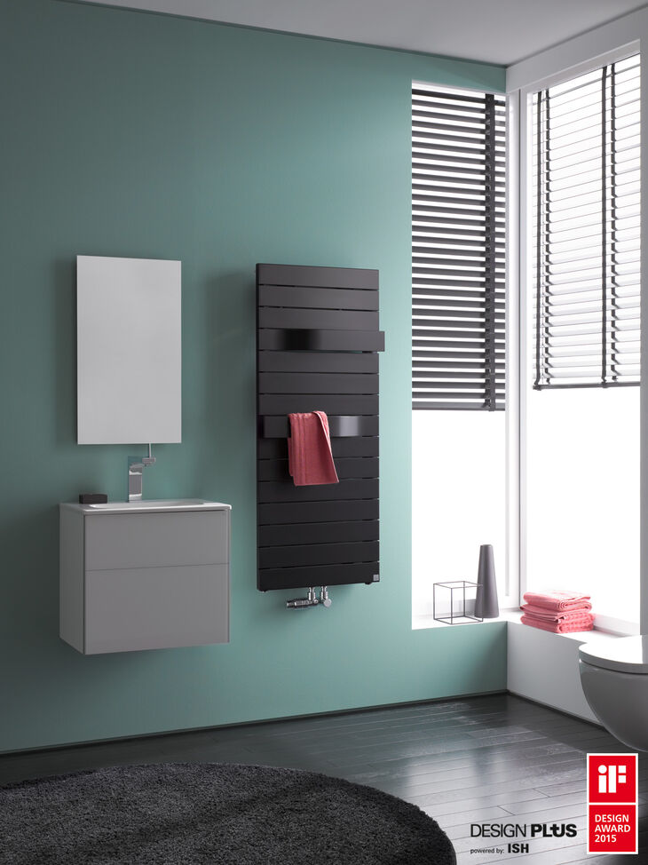 Badheizörper schwarz an der Wand montiert mit Handtuch. Designpreise für Heizkörper. Waschplatz mit Badspiegel.