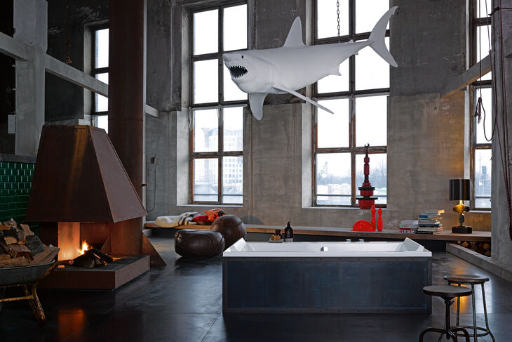 Industrielook Badezimmer mit freistehender Badewanne und einem Kamin mit Echtfeuer. Dekoration Hai an der Decke. Duravit ME by Starck.
