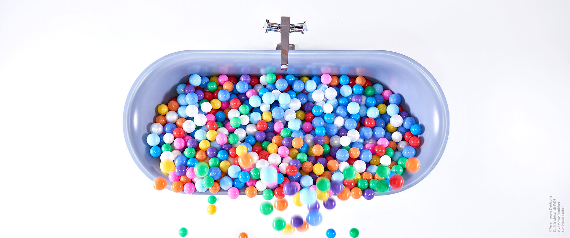 Bunte Kugeln liegen in einer Badewanne in blauer Farbe.