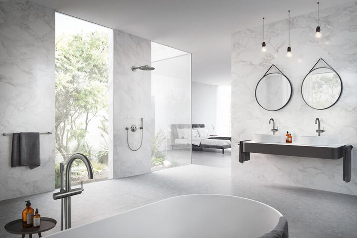 Badezimmermilieu hell mit runden Armaturen in chrom. Waschplatz mit Aufsatzwaschbecken und Badewanne.