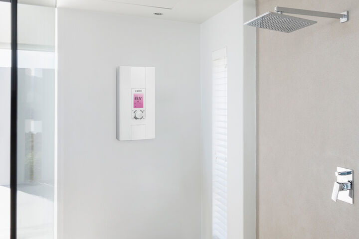 Weisser Durchlauferhitzer an der Wand neben der Dusche montiert mit Display.
