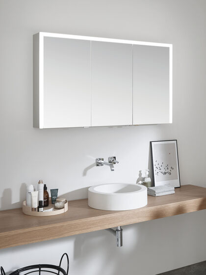 Geschlossener Spiegelschrank Elegant-Line 2.0 von SPRINZ mit dreiseitiger, angeschalteter LED-Beleuchtung und in der Korpusfarbe Aluminum Matt. 