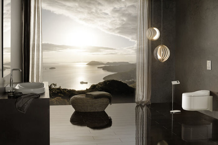 Stimmungsvolles Badezimmer mit Waschplatz und Dusch-WC Sensia Arena von Grohe. Ein großes Fenster mit Blick auf Meer und Inseln lässt das Abendlicht in den Raum. 