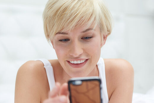 Blondes SPLASH Model im Top mit Blick auf das Smartphone.