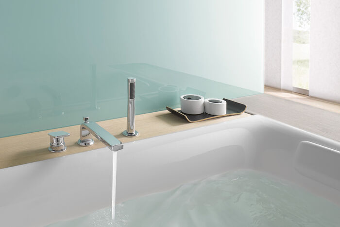 Eckige Design Badewannenarmatur seitlich montiert. Wasser läuft in die Badewanne.