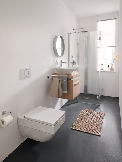 Ein langes und schmales Bad mit Fenster kann ebenso mit einer Dusche ausgestattet werden: In der Serie LIGA von Kermi gibt es eine Pendel-Falttür, die sich in U-Form als Spritzschutz aufklappen lässt über einem ebenen Duschboden.