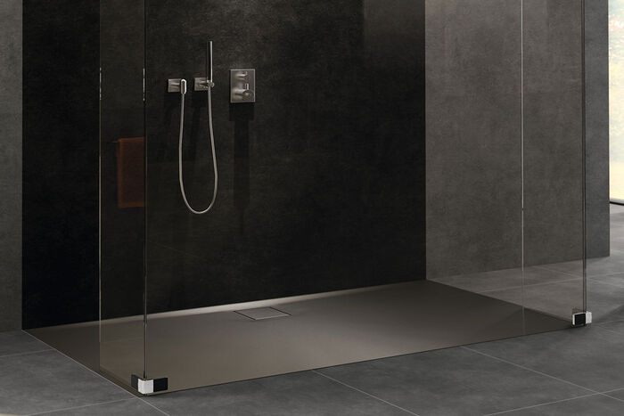 Schwarz-graue Duschkabine, in der eine Easy Flat Duschfläche von HUEPPE eingelassen ist. Rechts und Links der Dusche befinden sich Glaswände.