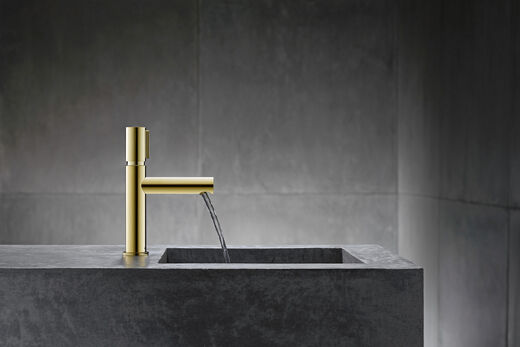 AXOR Uno Kurze goldene Waschtischarmatur mit fließendem Wasser.