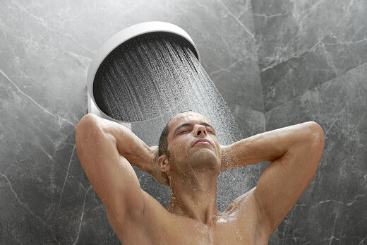 Wie ein Sommerregen: Mann genießt den Powderrain-Strahl unter der Rainfinity Kopfbrause von hansgrohe.
